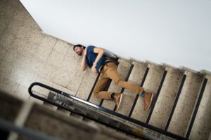 PERSON LAYING AT THE FOOT OF THE STAIRS AFTER A FALL