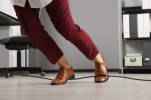 WORKER TRIPPING OVER A STRAY COMPUTER CABLE IN THE OFFICE