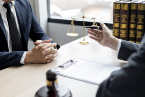 A No Win No Fee solicitor advises a claimant at a desk containing claim paperwork, gavel and scales.