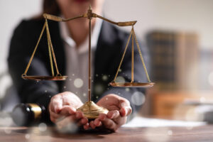Hit and run lawyer sat at a desk holding a justice scale. 