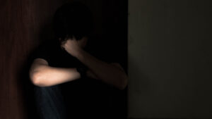 A dark image of a man crouching in the dark.