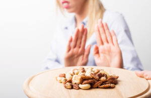 A woman pushes away a plate of nuts.