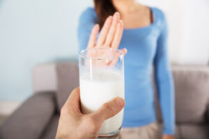 A woman refuses a glass of milk. 
