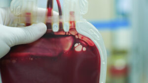 A medical professional wearing late gloves while holding a blood bag
