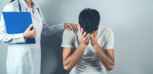 A doctor consoling a patient with their head in their hands after learning that they have been affected by surgical negligence