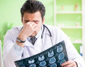 A doctor holding his head in disappointment while holding a scan that he has misread, causing a patient to suffer harm unnecessarily 