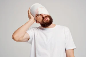 A man winces in pain wearing a bandage after suffering a head injury