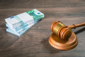 A gavel and pile of bank notes on a wooden table 