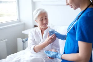 A nurse issues medication to a patient in a care home. 
